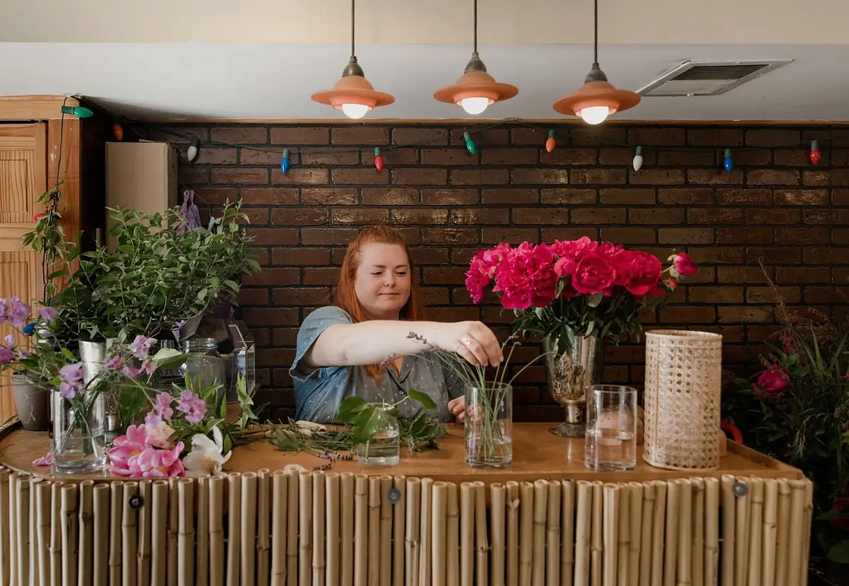 A florist at a flower counter arranging stems (illustrative photo)