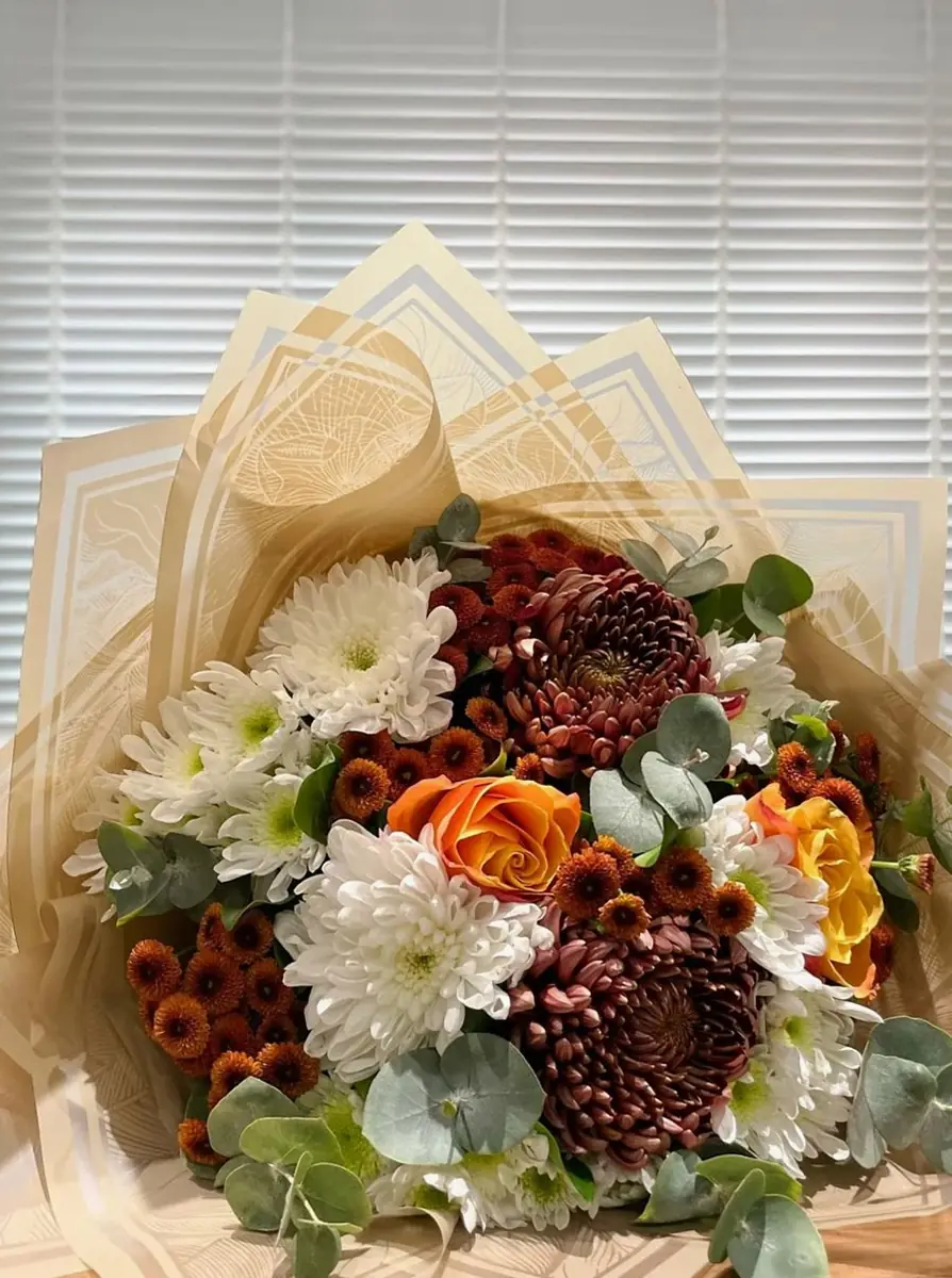 Autumn bouquet of dahlias and chrysanthemums in cream wrapping (illustrative photo)